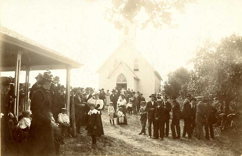People gathering in front of Nora UU church and the summer cottage